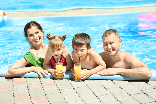 Ευτυχισμένη οικογένεια με ποτήρια χυμό ανάπαυσης στην πισίνα - Φωτογραφία, εικόνα