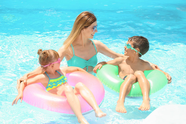 Счастливая мать и дети с надувными кольцами отдыхают в бассейне
 - Фото, изображение