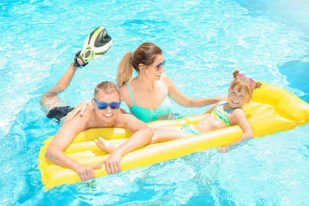 Familia feliz con colchón inflable en la piscina
 - Foto, Imagen