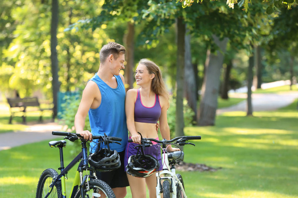 Спортивная молодая пара с велосипедами в парке
 - Фото, изображение
