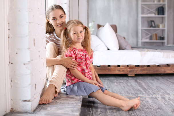 Happy mother with cute daughter sitting on floor at home - Photo, Image