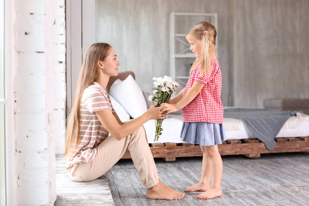 Söpö pieni tyttö antaa kukkia äidilleen kotona
 - Valokuva, kuva
