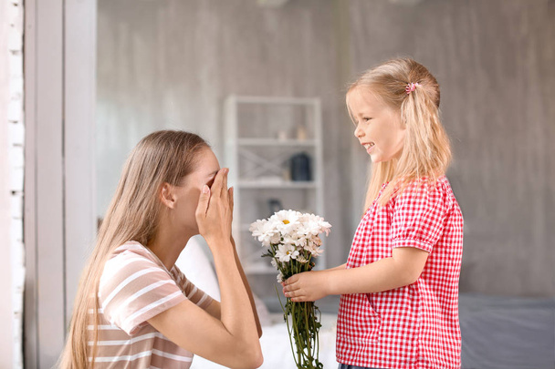 Cute little girl giving flowers to her mother at home - Fotoğraf, Görsel