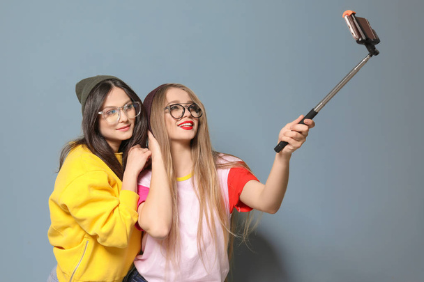 Attractive young women taking selfie on grey background - Valokuva, kuva