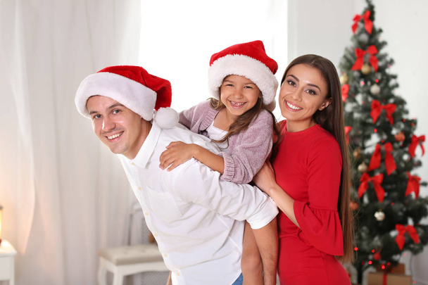 Happy parents and child having fun near Christmas tree at home - Photo, image