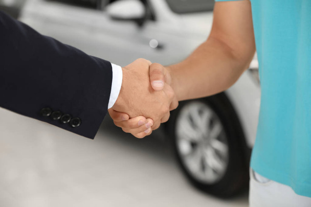 Customer and salesman shaking hands in car salon - Photo, image