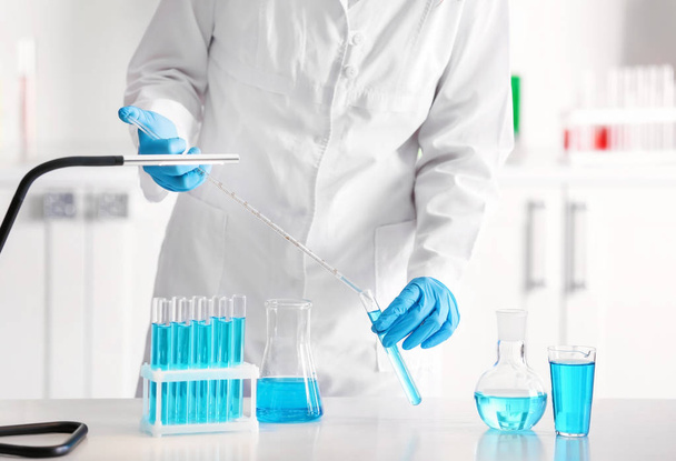 Вчений кидає кольорову рідину в пробірку в лабораторію
 - Фото, зображення