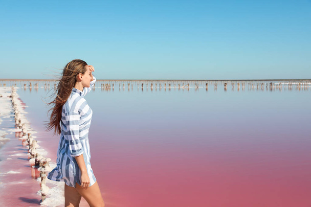 Beautiful woman posing near pink lake on summer day - Foto, afbeelding