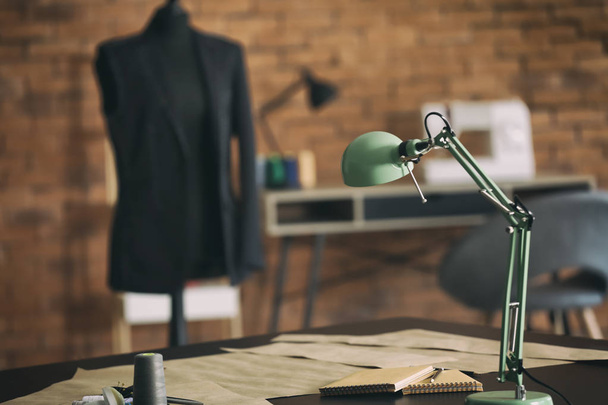 Стол с лампой и узорами шитья в мастерской портного
 - Фото, изображение