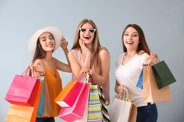 Beautiful young women with shopping bags on light background - Фото, зображення