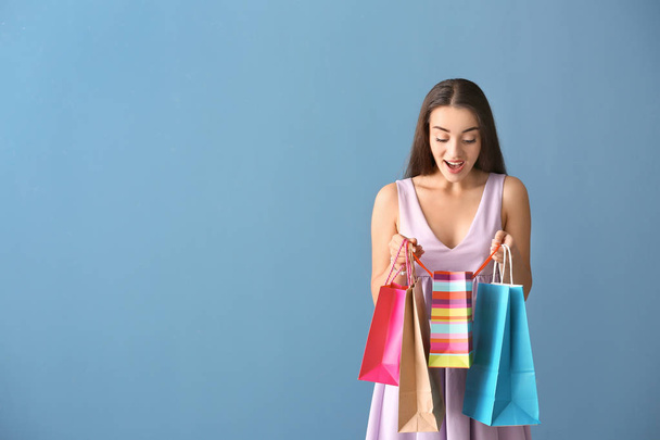 Mujer joven emocional con bolsas de compras en el fondo de color
 - Foto, imagen
