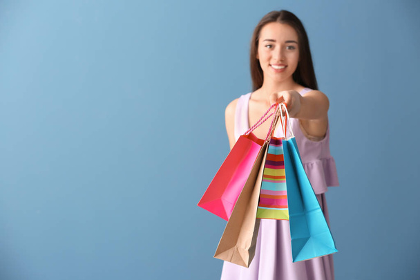 Bella giovane donna con borse della spesa su sfondo di colore - Foto, immagini