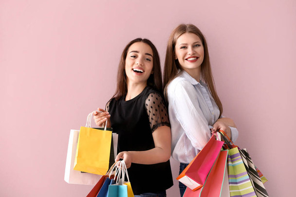 Красивые молодые женщины с сумками для покупок на цветном фоне
 - Фото, изображение
