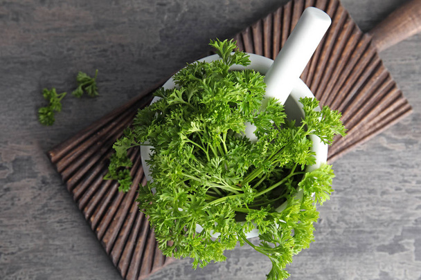 Mortar with fresh green parsley on grey background, top view - Fotografie, Obrázek