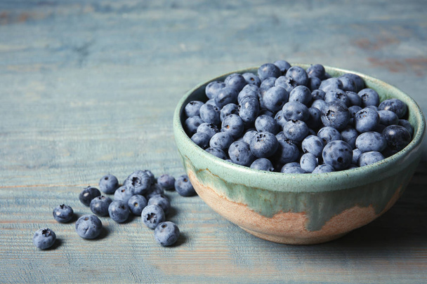 Crockery with juicy and fresh blueberries on wooden table. Space for text - Foto, Imagen