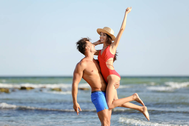 Happy young couple having fun at beach on sunny day - Fotografie, Obrázek