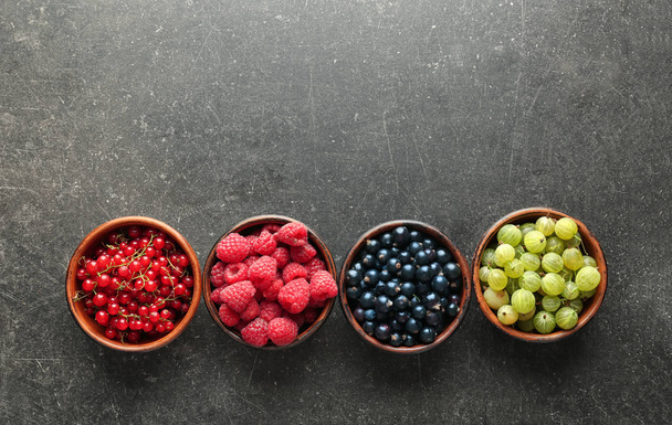 Bowls with various ripe berries on grey background, top view - Фото, зображення