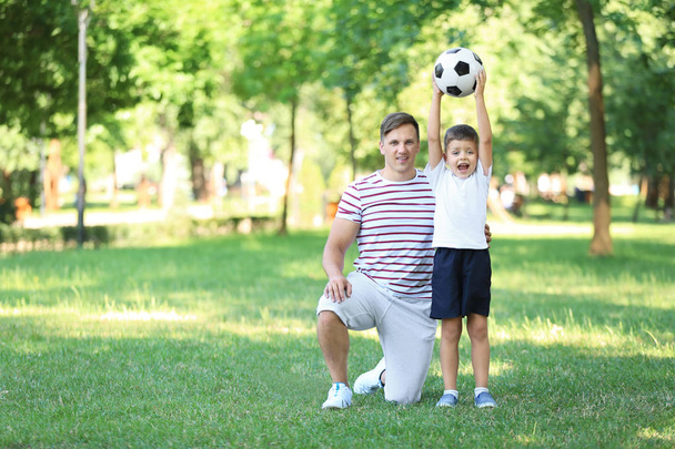 Μικρό αγόρι και ο μπαμπάς του με την μπάλα ποδοσφαίρου στο πάρκο - Φωτογραφία, εικόνα