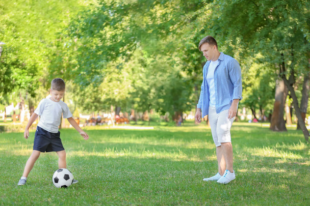 Piccolo ragazzo con suo padre che gioca a calcio nel parco
 - Foto, immagini