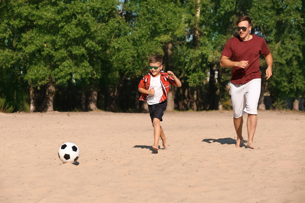 Kleiner Junge mit seinem Vater beim Fußballspielen am Sandstrand - Foto, Bild