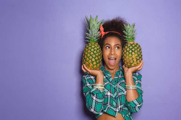 Beautiful African-American woman with pineapples on color background - Foto, Imagem