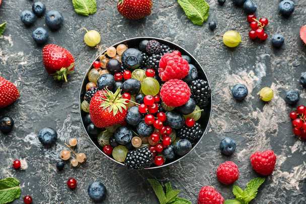 Bowl with delicious ripe berries on grey textured background - Photo, Image