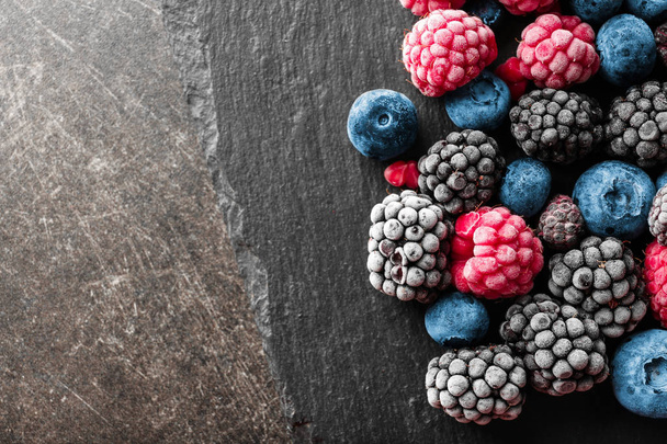 Тарелка с вкусными замороженными ягодами на сером фоне
 - Фото, изображение