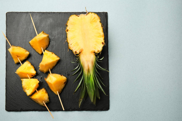 Palos con trozos de piña madura y la mitad de la fruta sobre fondo claro
 - Foto, imagen