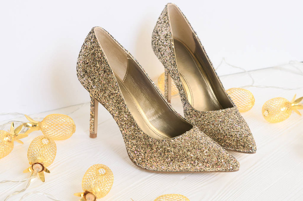 Womens gold chunky glitter pumps. Shoes for wedding, christmas, new year, evening, cocktail, night out. Golden stiletto heels. Flat lay. Footwear on white wooden background with copy spac - Photo, Image
