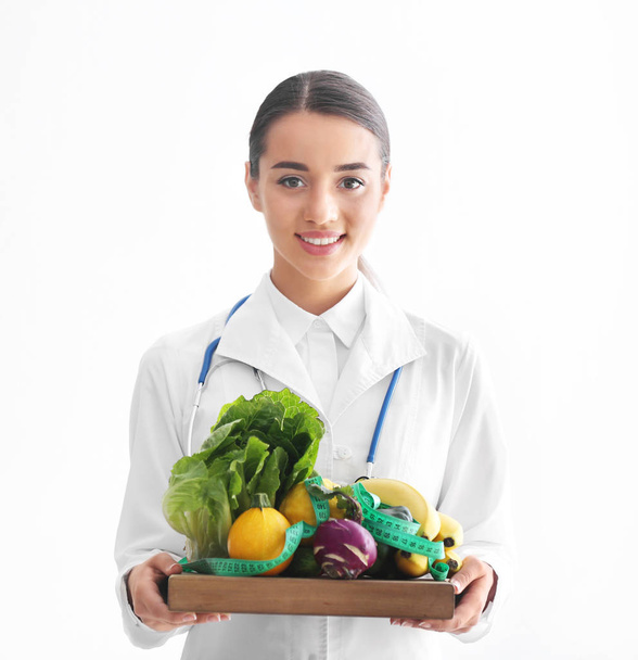Nutrizionista femminile che tiene tavola di legno con verdure e frutta sane su sfondo bianco
 - Foto, immagini