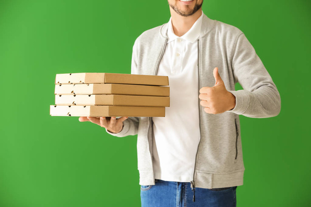 Hombre con cajas de pizza mostrando gesto de pulgar hacia arriba en el fondo de color. Servicio de entrega de alimentos
 - Foto, Imagen