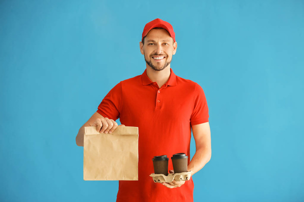 Άνθρωπος με χάρτινη σακούλα και τα φλυτζάνια του καφέ στο χρώμα φόντου. Υπηρεσία παράδοσης τροφίμων - Φωτογραφία, εικόνα