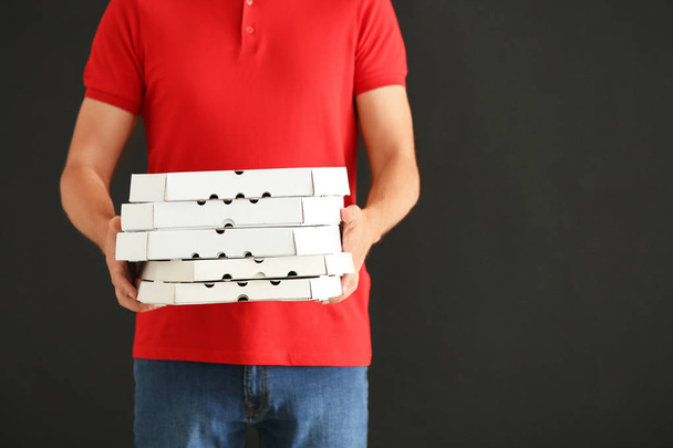 Mann mit Pizzakartons auf grauem Hintergrund. Essenslieferdienst - Foto, Bild