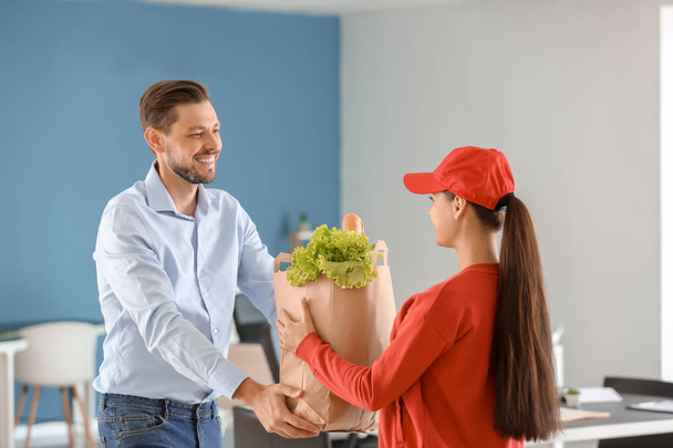 Young woman delivering food to customer indoors - Photo, Image