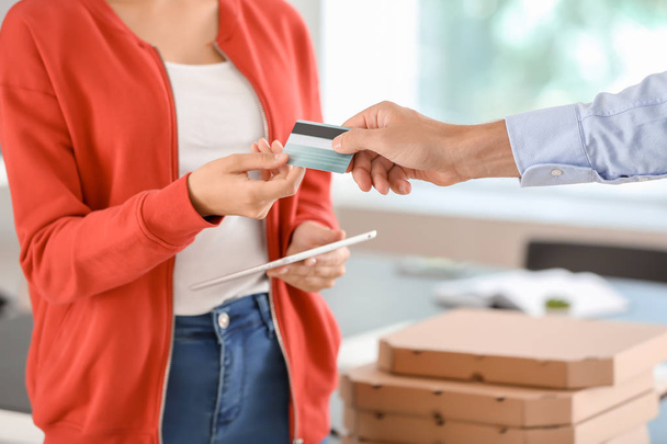 Hombre pagando pizza con tarjeta de crédito en el interior, primer plano. Servicio de entrega de alimentos
 - Foto, Imagen