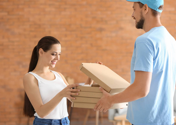 Man delivering pizza to customer indoors - 写真・画像