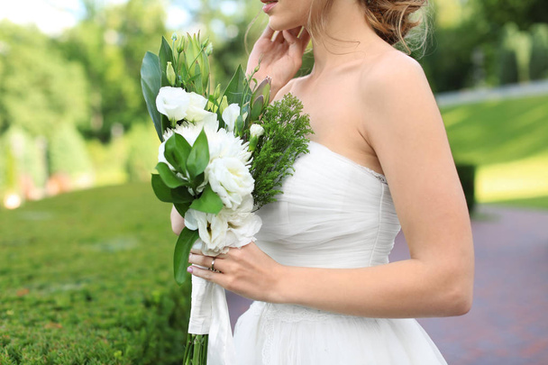 Beautiful young bride with wedding bouquet outdoors - Fotó, kép
