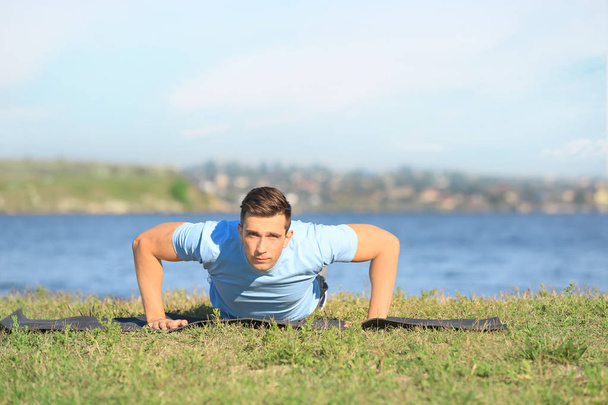 Sporty young man training near river outdoors - Фото, зображення