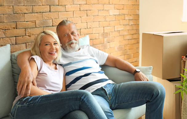 Mature couple resting on sofa after moving into new house - Photo, Image