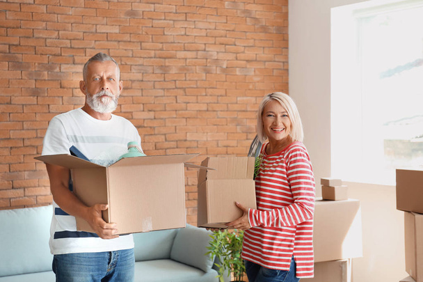 Mature couple with boxes indoors. Moving into new house - Photo, Image