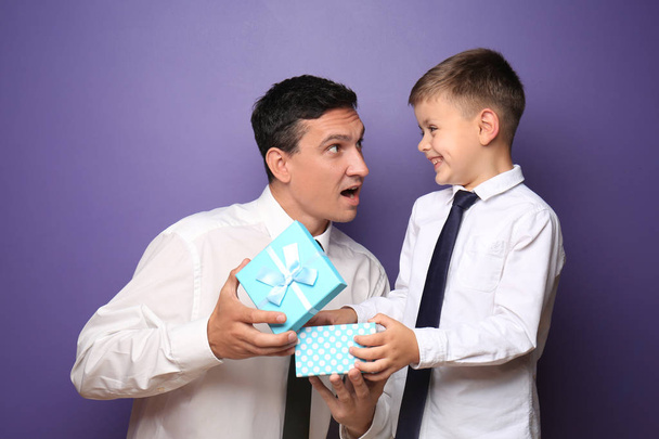 Little boy giving present to his father on color background - Фото, зображення