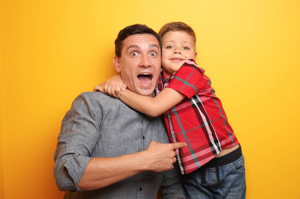 Emotional portrait of little boy and his dad on color background - Photo, image