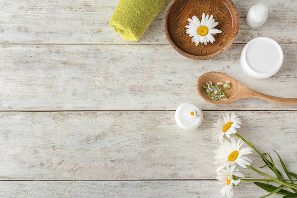 Kompozycja z kosmetyków naturalnych i kwiatów rumianku na podłoże drewniane - Zdjęcie, obraz