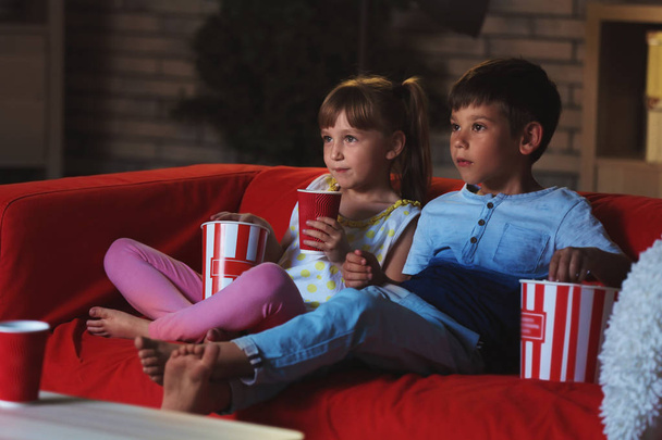 Cute children watching TV on sofa in evening - Foto, immagini