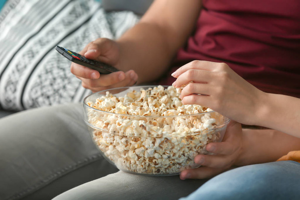 Jong koppel eten popcorn tijdens het kijken naar Tv thuis, close-up - Foto, afbeelding