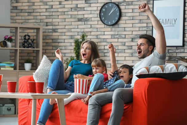 Сім'я дивиться телевізор на дивані вдома
 - Фото, зображення