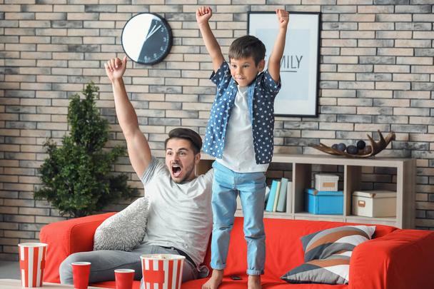 Buon padre e suo figlio che guardano la TV sul divano a casa
 - Foto, immagini