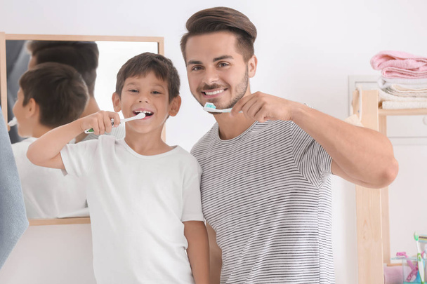 Jongetje en zijn vader tandenpoetsen in de badkamer - Foto, afbeelding