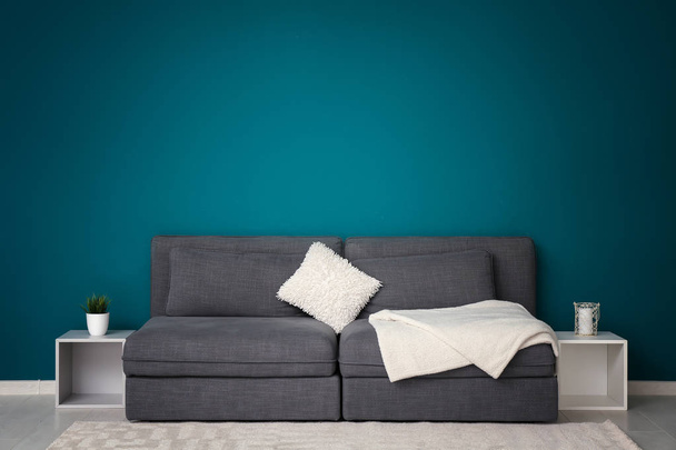 Интерьер гостиной со стильным удобным диваном возле цветной стены
 - Фото, изображение