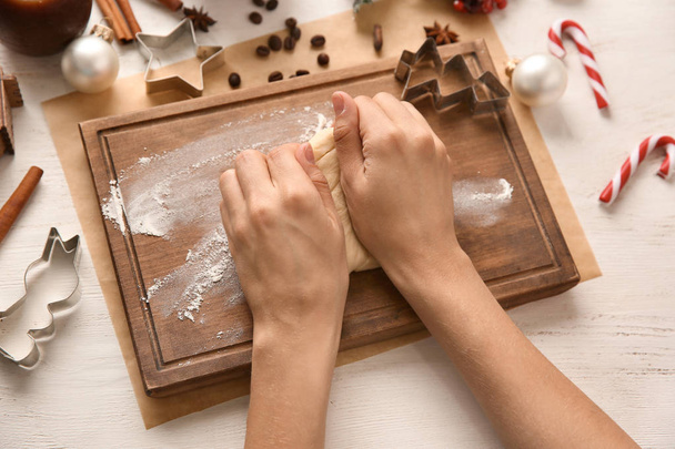 Женщина месит тесто для рождественской пекарни за деревянным столом
 - Фото, изображение